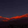 Sierra Nevada peaks lit by alpenglow at sunrise, viewed across the dark floor of Death Valley, California. Panoramic fine art landscape photograph. Large format.