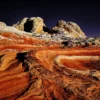 Swirling cross-bedded Navajo sandstone at White Pocket in burning orange, red, and gold under a dark sky, Vermilion Cliffs National Monument, Arizona. Fine art landscape photograph. Fujifilm GFX medium format.