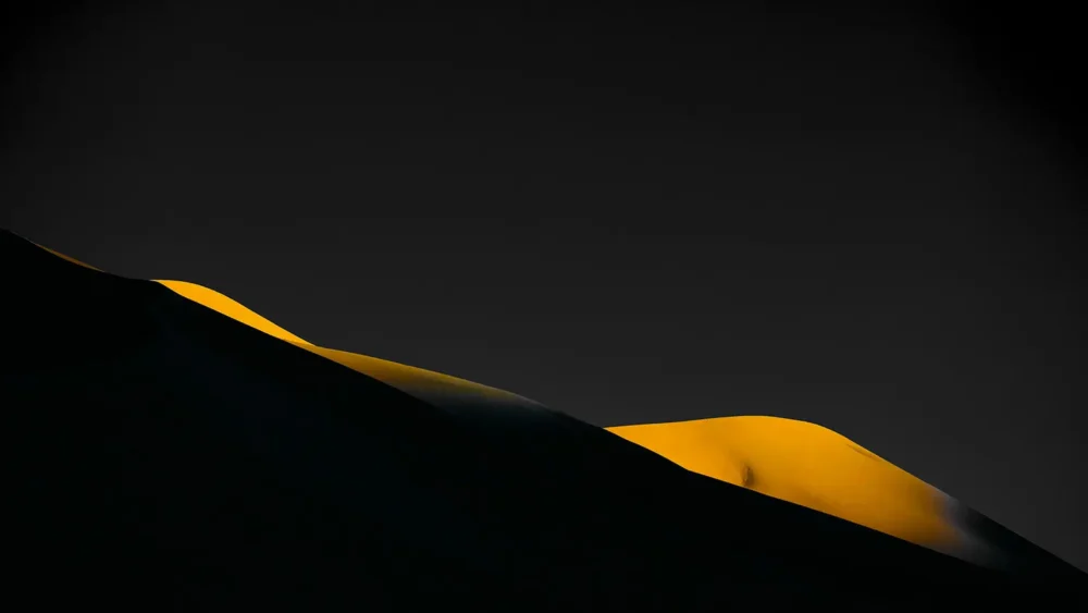 A single golden-lit dune ridge rises against pure black shadow at the first light of sunrise, Eureka Dunes, Death Valley National Park, California. Signature Series black-field fine art photograph. Fujifilm GFX medium format.