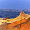 Golden and rust-coloured eroded badlands at Zabriskie Point, Death Valley National Park, at morning light. Three-frame Hasselblad panoramic photograph.