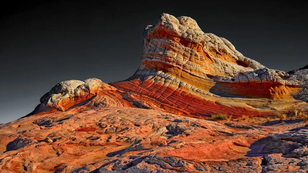 Swirling red, ochre, and cream Navajo sandstone at golden hour under a dramatic sky, White Pocket, Vermilion Cliffs National Monument, Arizona. Fujifilm GFX.
