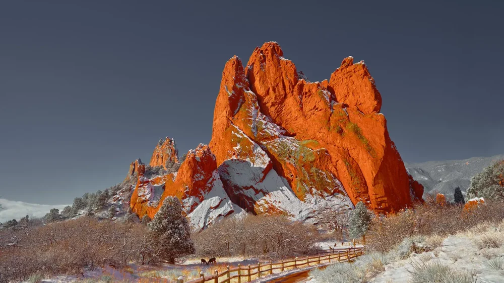 Snow-dusted red sandstone monoliths of Garden of the Gods rise against a deep blue winter sky, Colorado Springs, Colorado. Fine art landscape photograph with alpine winter conditions. Signature Series.