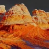 The cross-bedded Navajo sandstone formations at White Pocket ignite in burning orange and warm cream at direct sunrise light against a dramatic dark sky, Vermilion Cliffs National Monument, Arizona. Fine art landscape photograph. Fujifilm GFX medium format