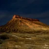 An isolated sandstone ridge lit by the last warm light of day against a deep blue dusk sky, Badlands, Utah. Fine art landscape photograph, large format