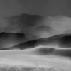 Layered dune forms with visible wind-drift patterns and distant ridgeline at Eureka Dunes, Death Valley National Park. Black and white atmospheric fine art landscape photograph. Fujifilm GFX medium format