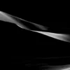 A single sculptural dune form catches sidelight and appears suspended against pure black shadow at Eureka Dunes, Death Valley National Park. Black and white minimalist fine art photograph. Fujifilm GFX medium format.