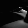 A single white dune ridge sweeps across pure black shadow like a cresting wave at Eureka Dunes, Death Valley National Park. Black and white panoramic fine art photograph. Fujifilm GFX medium format